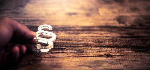 Startseite Heilpraktikergesetz Hand, die ein helles Paragraphenzeichen festhält, auf dunklem Untergrund.